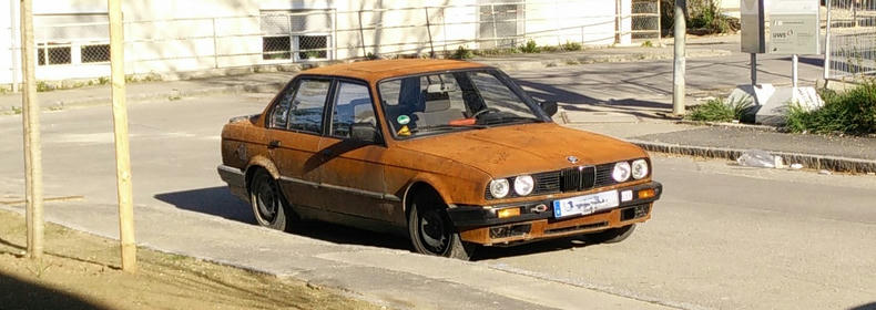 Open Source Software in cars—a model for success An old BMW with a fully rusted body parked on a street.